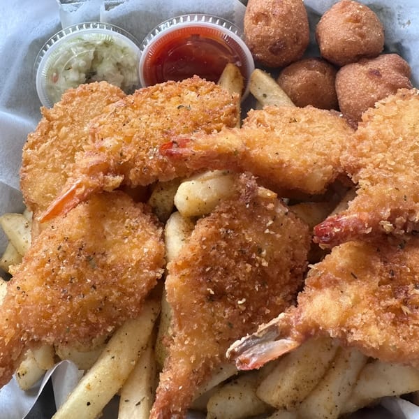 Fried shrimp and french fries with hush puppies, coleslaw, and cocktail sauce.